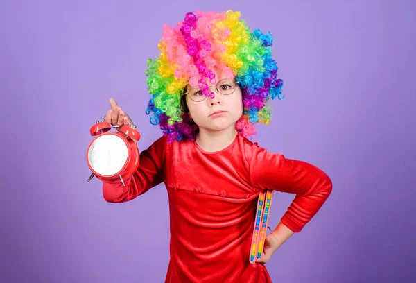 Zorg voor uw tijd. Meisje schattig speelse Kid dragen krullend regenboog pruik. Het leven is leuk. Gelukkige kindertijd. Gelukkig klein meisje. Internationale Kinder dag. Kinderopvang. Gelukkige momenten. Kind Hold wekker — Stockfoto