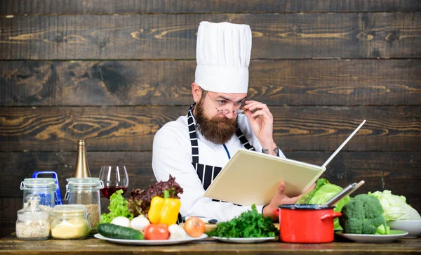 Folgen Sie dem Rezept. Ein bärtiger Mann kocht in der Küche. Biolebensmittel essen. frisches Gemüse. Vitamin. Der Mensch benutzt Geschirr. Profi-Koch in Kochuniform. gesunde Ernährung und vegetarisch — Stockfoto