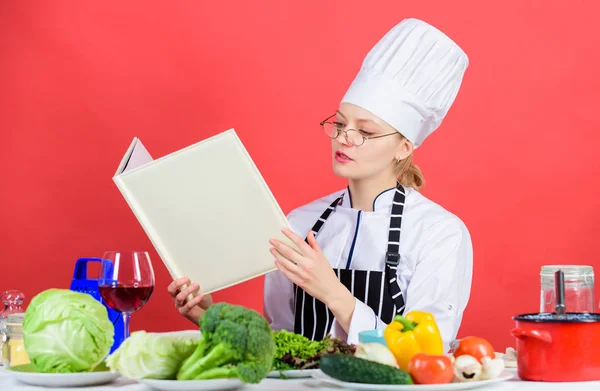 Koken en serveren gezond vegetarisch menu. Mooie vrouwelijke kok lezen menukaart bij keuken tafel. Schattig vrouw leren restaurant menu voor een dag. Menu eten en drinken lijst — Stockfoto