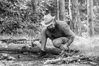 Şenlik için Ultimate guide. Nasıl açık havada şenlik ateşi kurmak. Ormanda twigs veya ahşap sopa bir piramit gibi duran ve yaprakları altında yer. Adam hasır şapka ormandaki şenlik ateşi hazırlar