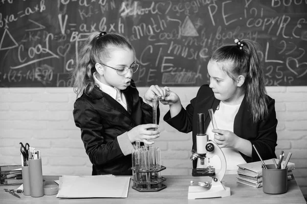 Göra att studera kemi intressant. Pedagogiska experiment konceptet. Mikroskop och provrör på bordet. Utföra kemiska reaktioner. Grundläggande kunskaper i kemi. Flickor klasskamrater studera kemi — Stockfoto