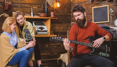 Adam gitar çalmak rüya gibi bakışla sakallı. Müzik, huzur kavramı üzerinde meditasyon hipster sakallı adam. Müzisyen kadınlar güzel tunes ile büyüleyici. Performans retro kamera kaydı kızlar