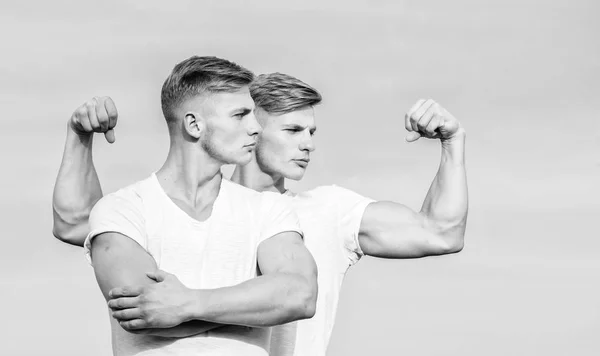 Mode de vie sportif et corps sain. Des jumeaux séduisants. Beaux jumeaux forts. Hommes jumeaux frères musclés fond ciel. Hommes musclé musclé athlète bodybuilder posant avec confiance dans des chemises blanches — Photo