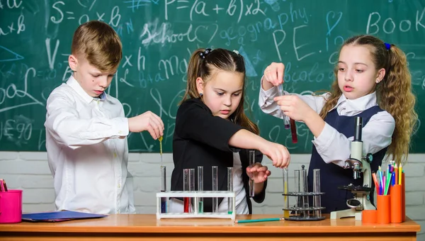 Μελέτη των υγρών κρατών. Οι μαθητές της ομάδας σπουδάζουν χημικά υγρά. Σχολικό εργαστήριο. Τα κορίτσια και το αγόρι διεξάγουν πειράματα με υγρά. Ομαδική δουλειά. Δοκιμαστικούς σωλήνες με πολύχρωμες υγρές ουσίες — Φωτογραφία Αρχείου