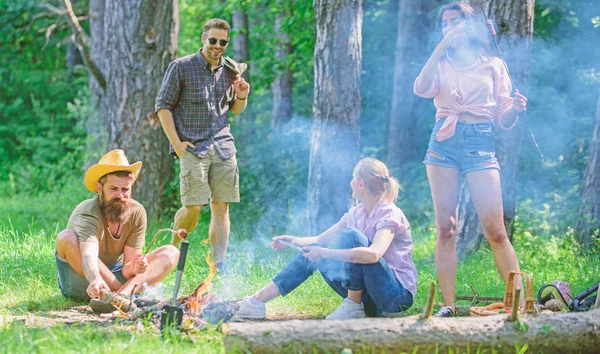 Ci riuniamo per un bel picnic. Amici incontro a prato per appendere fuori e preparare salsicce arrosto snack sfondo natura. Unisciti al picnic estivo. Azienda che si diverte mentre arrostisce salsicce su bastoncini — Foto Stock