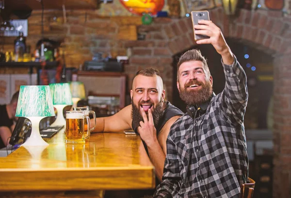 Enviar selfie a los amigos de las redes sociales. Hombre en el bar bebiendo cerveza. Tome una foto selfie para recordar la gran noche en el pub. Comunicación en línea. Hombre barbudo hipster mantenga el teléfono inteligente. Tomando concepto de selfie —  Fotos de Stock