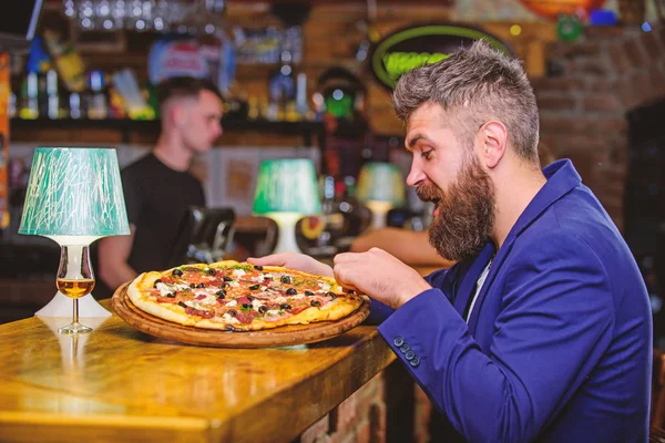 Enjoy your meal. Cheat meal concept. Hipster hungry eat italian pizza. Pizza favorite restaurant food. Fresh hot pizza for dinner. Hipster client sit at bar counter. Man received delicious pizza