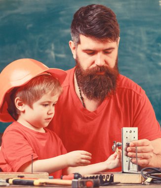 Mens kavramı çalışır. Evlat, çocuk koruyucu kask yapar elle meşgul tamiri, el sanatları ile baba yok. Baba sakallı sınıfta, arka plan kara tahta araçlarını kullanmak için küçük oğlu öğretim