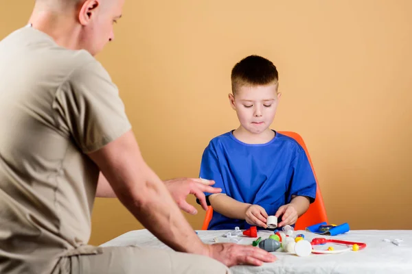 Hospital worker. Medical service. Kid little doctor sit table medical tools. Health care. Pediatrician concept. Boy cute child and his father doctor. Medical examination. Child care kindergarten — Stock Photo, Image