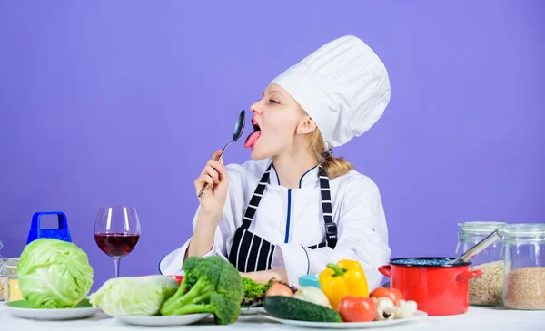 惊人的味道。女厨师在餐桌配料附近戴帽子围裙。女孩可爱的厨师教烹饪。最好的烹饪食谱，尝试在家里。将食材变成美味佳肴。烹饪技巧 — 图库照片