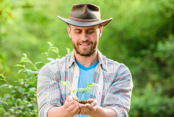 Eco farm worker. Earth day. farming and agriculture cultivation. Gardening. happy earth day. Eco living. muscular ranch man in cowboy hat care plants. successful farmer hold plant in ground in hands