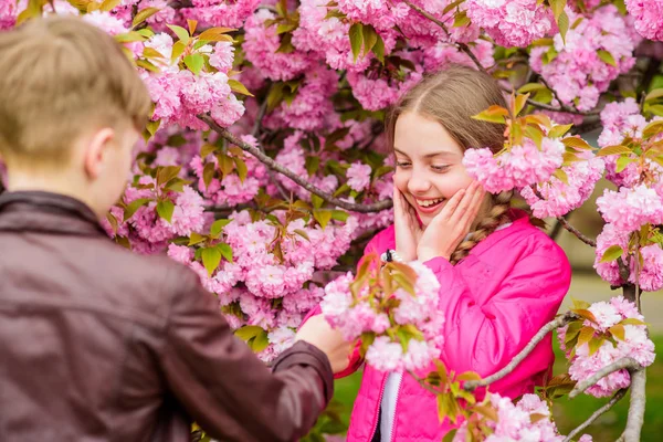 Adolescentes románticos. Niños disfrutando de flor de cerezo rosa. Flor tierna. Un par de niños con flores de sakura. Niña disfrutar de flores de primavera ramo. Dándole todas las flores. Sorprendente. — Foto de Stock