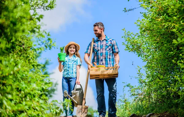 Garden works. Spring garden. Spring gardening checklist. Father and daughter with shovel and watering can in garden. It is time to plant prepare beds and care for lawn. Pick out flats favorite plants