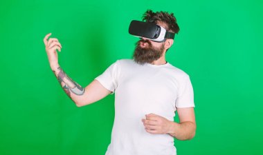 Vr gözlük, yeşil arka planda sakallı adam. Hipster gitarist hevesli yüzündeki modern teknoloji eğlence için kullanın. Vr gözlüklü öğrenin gitar müzik çalmak. VR müzisyen kavramı
