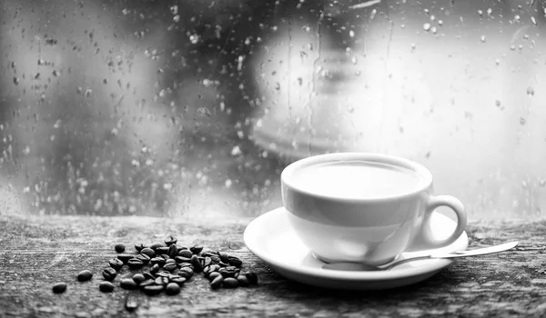 Autunno tempo nuvoloso migliore con caffeina bere. Mi godo il caffe 'nei giorni di pioggia. Caffè fresco tazza bianca e fagioli sul davanzale della finestra. Finestra di vetro bagnato e tazza di caffè caldo. Caffè mattina rituale — Foto Stock