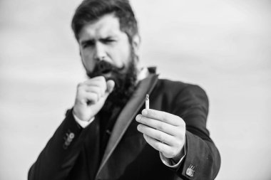 Adam sigara nikotin etkisi tadını çıkarın. Sakallı bıyıklı adam sigara tutun. Sigara her şeyi can sıkıntısı ile öfke yönetimi için bize yardım. Sakallı hippi sigara sigara gökyüzü arka plan