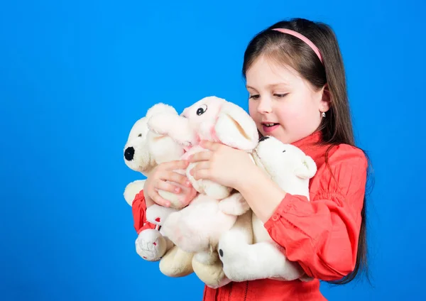 Pequeña niña sonriendo cara con juguetes. Feliz infancia. Niña jugar con juguete suave osito de peluche. Hay muchos juguetes en sus manos. Recoger juguetes hobby. Queridos recuerdos de la infancia. Concepto de infancia — Foto de Stock