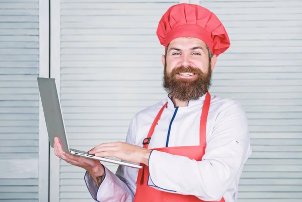 Lebensmittelgeschäft online. Lieferservice. Chef-Laptop in der Küche. Kochschule. Hipster in Hut und Schürze kaufen Produkte online. Online einkaufen. Mann Koch Suche Online-Zutaten Kochen Lebensmittel — Stockfoto