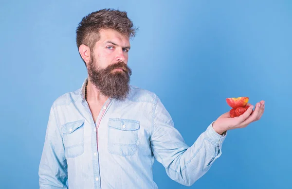 髭を生やした男は有機的な治療を提供しています。男はイチゴとリンゴの果物を試してみることを提供しています青の背景を扱う。私はあなたのための御馳走を — ストック写真