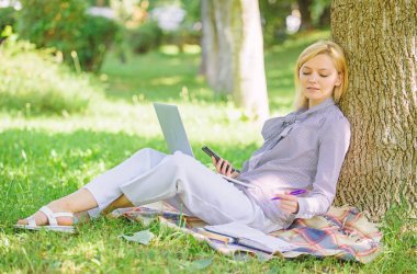 Eğitim teknolojisi ve internet kavramı. Dizüstü bilgisayar işleriyle açık havada ağaç gövdesinde yağsız olan kadın. Park içinde laptop ile kız iş çimenlerin üzerinde oturmak. Doğal çevre ofisi. İş açık havada faydaları