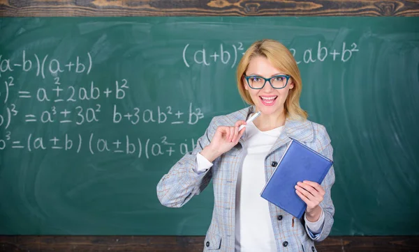 Ensinar a atividade multifacetada complexa. Professor mulher inteligente com livro explicar tópico perto quadro. O que faz um grande professor. Professor da escola explicar as coisas bem e tornar o assunto interessante — Fotografia de Stock