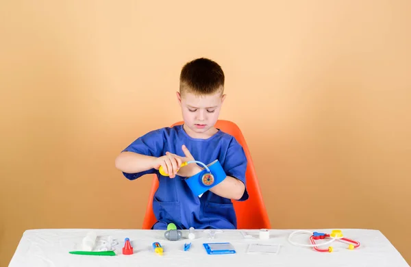 Medical examination. Medical education. Play game. Boy cute child future doctor career. Healthy life. Health care. Kid little doctor sit table with stethoscope and medical tools. Medicine concept