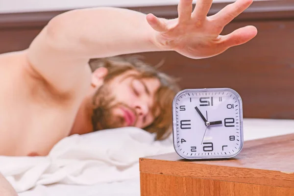 Jovem alegre está acordando depois de dormir de manhã. Bonito homem usando relógio na cama depois de acordar de manhã. Homens na cama. — Fotografia de Stock