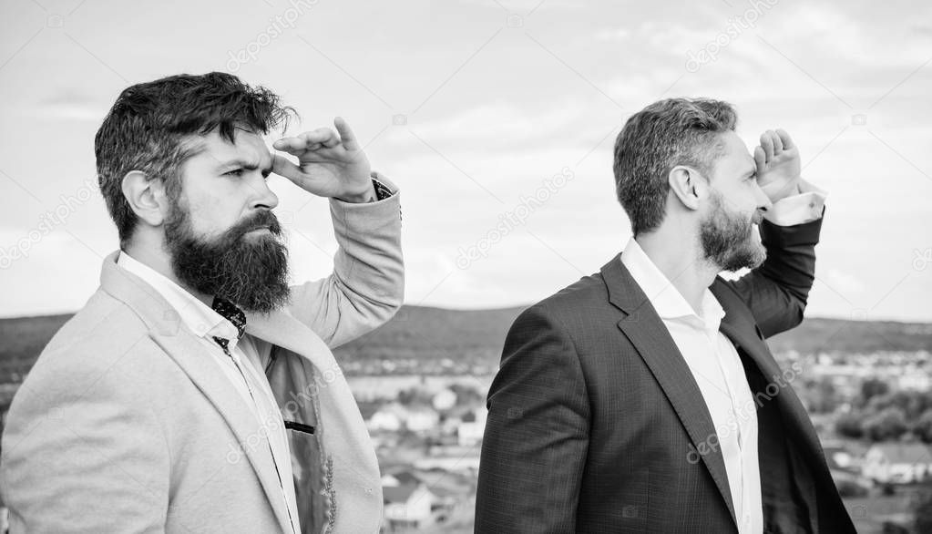 Developing business direction. Men formal suit managers looking at opposite directions. Changing course. New business directions. Businessmen bearded faces stand back to back sky background