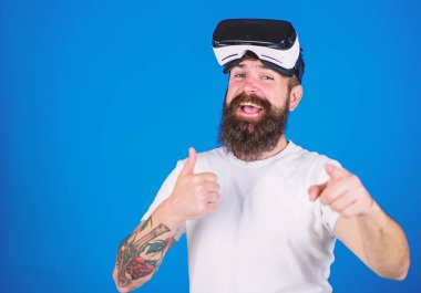 Sakal ve bıyık Vr gözlük, mavi arka plan ile olan adam. VR teknolojisi kavramı. Hipster mutlu yüz ileriye dönük jest ve yukarı gösterir. Adam Vr gözlük veya baş ile görüntü monte
