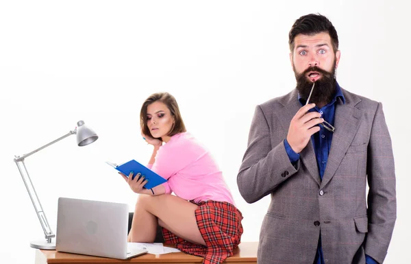 The boss knows everything she does. Bearded boss with pretty employee working in background. Serious boss and sexy coworker in office. Boss and subordinate