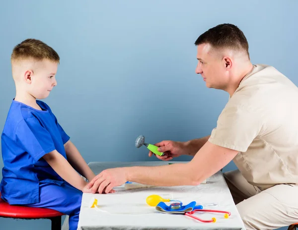 의료. 육아. 주의 깊은 소아과 의사가 아이의 건강을 확인합니다. 건강 검진. 의료 서비스. 남자 의사는 작은 소년 환자를 검사 테이블 의료 도구를 앉아있다. 소아과 의사 개념 — 스톡 사진