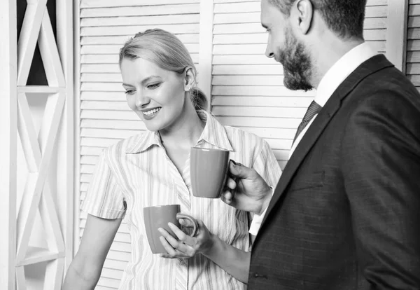 Dois jovens alegres em trajes formais segurando xícaras de café e discutindo algo enquanto trabalham juntos. Jovens colegas felizes ter tempo livre e beber café . — Fotografia de Stock