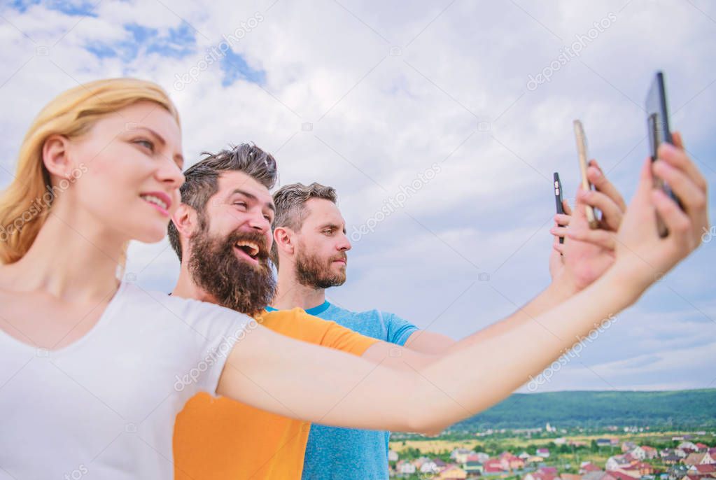 Being narcissistic. People enjoy selfie shooting on natural landscape. Sexy woman and men holding smartphones in hands. Best friends taking selfie with camera phone. Sharing selfie on social network