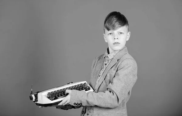 Vintage typography. Cute boy having typing machine. Small kid with vintage typewriter. Smart child using machanical vintage machine. Little boy holding vintage typewriter on blue background — Stock Photo, Image