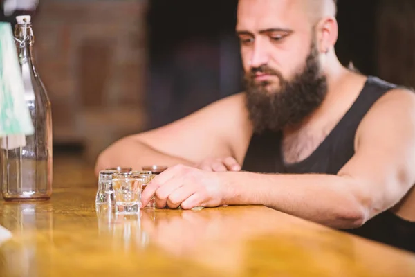 Hipster hombre brutal bebiendo alcohol pidiendo más bebidas en el mostrador del bar. Alcoholismo y depresión. El tipo pasa el tiempo libre en el bar con alcohol. Un borracho se sienta solo en el pub. Concepto adicto al alcohol — Foto de Stock