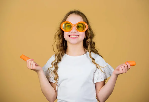 happy girl eat fresh carrot. summer vacation. little girl in fashion glasses. Vitamin nutrition. refreshing vitamin juice. Health care. Summer vitamin diet. Natural vitamin source. Vegetarian concept