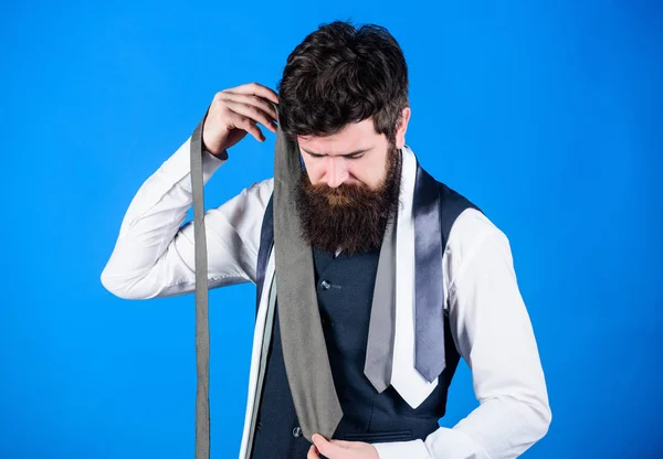 Hard choice to make. Bearded man choosing tie from luxury collection, choice concept. Salesman offering a good choice of design neckties. Brutal hipster making a choice