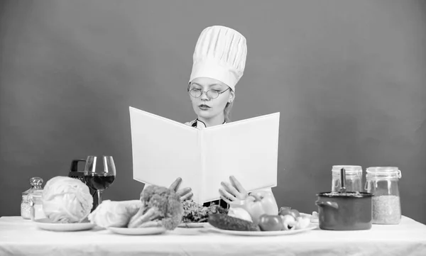 Culinary school concept. Female in hat and apron knows everything about culinary arts. Culinary expert. Woman chef cooking healthy food. Girl read book top best culinary recipes. Traditional cuisine