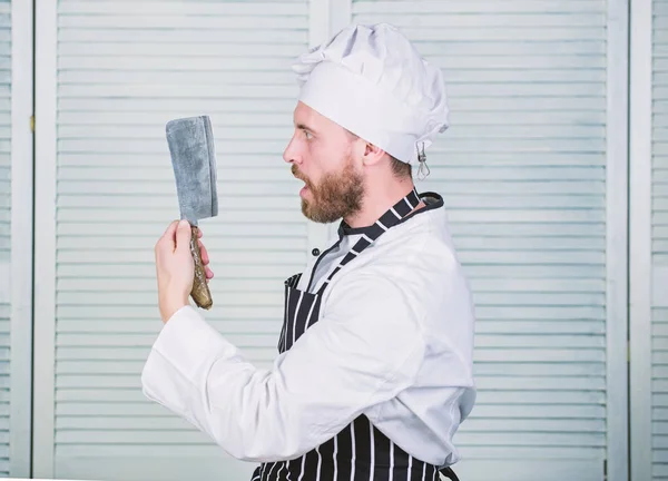 Podává se na hlavě. připraven k vaření šéfkuchař. jistý muž v zástěře a klobouk drží nůž. vařit v restauraci, jednotné. vousatý muž miluje jíst jídlo. Professional v kuchyni. kulinářská kuchyně — Stock fotografie