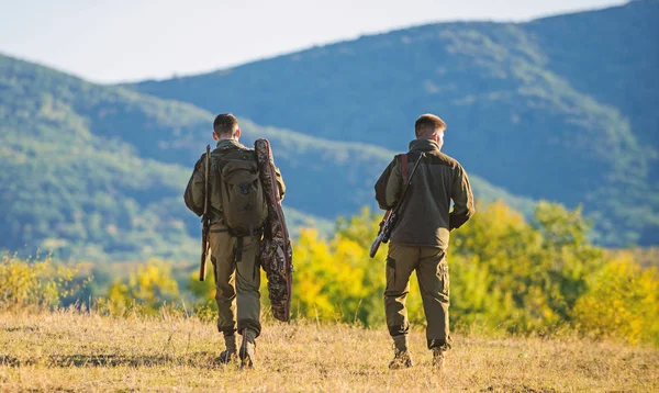 Hunters friends gamekeepers walk mountains background. Hunting with partner provide greater measure safety often fun and rewarding. Hunters rifles nature environment. Hunter friend enjoy leisure