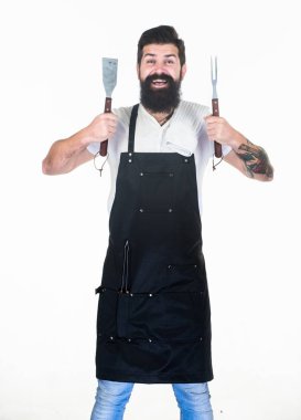 Harika bir aşçıdır. Pişirme gereçleri ile Mutlu ızgara aşçı. Sakallı adam yemek pişirmek ve barbekü servisi için çatal ve spatula tutuyor. Izgara önlük giyen usta aşçı. İş kıyafetleri nde baş aşçı. Cookout