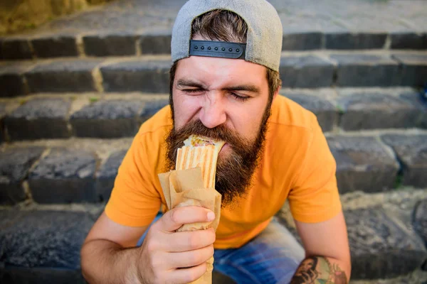 A melhor comida da cidade. Um homem barbudo a comer comida insalubre. Um tipo esfomeado que gosta de comida de rua. Hipster lanche com fast food durante a pausa para refeições nas escadas — Fotografia de Stock