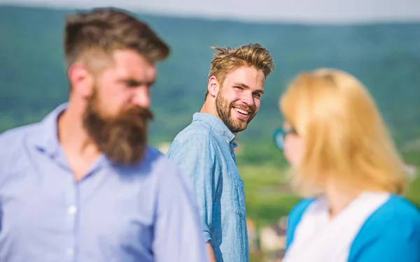 Man with beard jealous aggressive because girlfriend interested in handsome passerby. Jealous concept. Passerby smiling to lady. Husband strictly watching his wife looking at another guy while walk