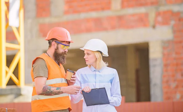 Relations entre les clients de la construction et l'industrie de la construction participante. Discuter du plan de progrès. Femme ingénieur et constructeur communiquent chantier de construction. Concept de communication équipe de construction — Photo