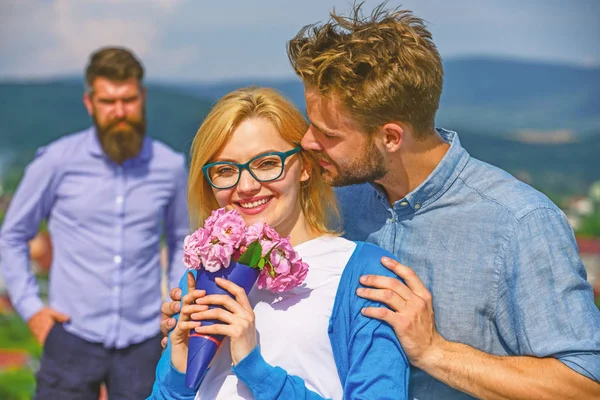 Pareja enamorada citas mientras celoso barbudo hombre viendo esposa engañándolo con amante. Pareja romántica pareja amantes flores ramo. Concepto de infidelidad. Los amantes abrazos al aire libre coquetear relaciones románticas —  Fotos de Stock