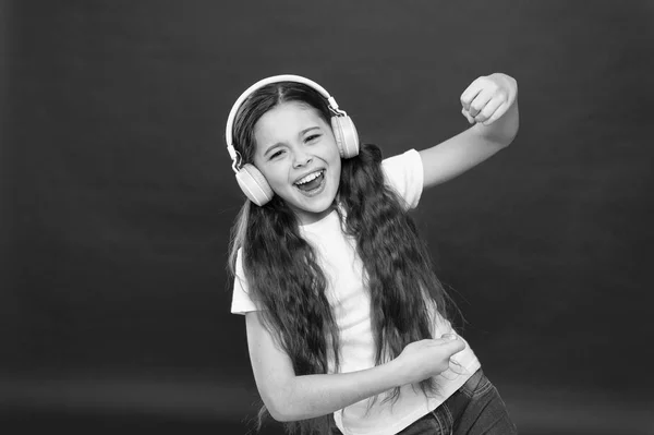 Cantando junto a una canción favorita. Niña escuchando música. Lindo ventilador de música con auriculares inalámbricos. Niña pequeña con auriculares estéreo. Pequeño niño que utiliza la tecnología para el ocio o la educación — Foto de Stock