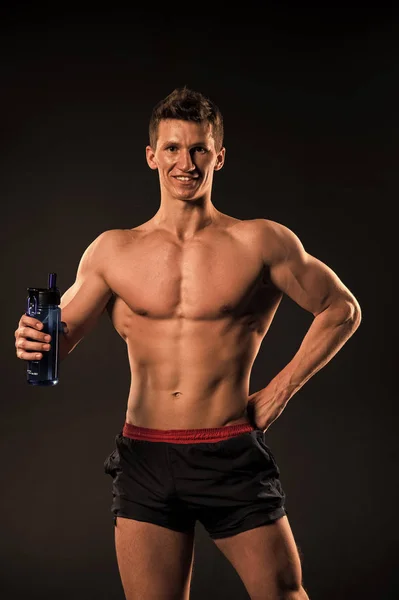 Man atleet met sport fles op donkere achtergrond — Stockfoto