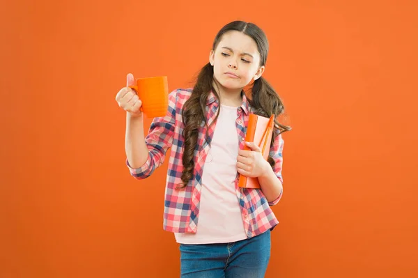 Esta no es mi taza de té. Chica insatisfecha mirando taza durante el almuerzo sobre fondo naranja. Niño en edad escolar almorzando. Niña en el almuerzo escolar. Niño bebiendo té o leche para el almuerzo — Foto de Stock