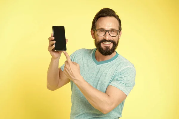 De man is enthousiast over de nieuwe mobiele mogelijkheden. Guy brillen vrolijke wijzend op de smartphone. Man gelukkig gebruiker communiceren applicatie voor smartphone. Man met baard interactie mobiele interface toepassing — Stockfoto