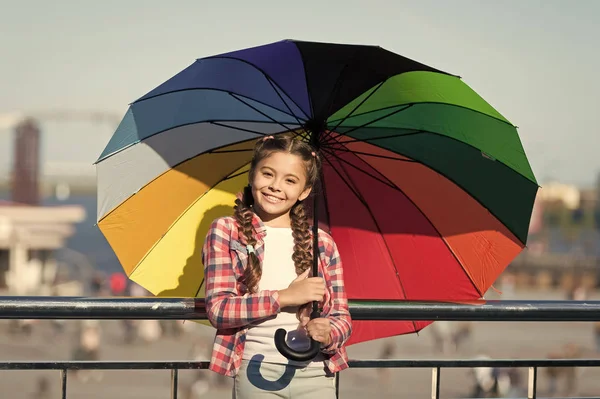 Pequeña chica bonita de pie con paraguas de colores. Chica en el puente. Escondiéndose del sol con paraguas. Tonos brillantes de chica estado de ánimo feliz. Esperando la lluvia bajo el paraguas — Foto de Stock